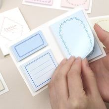 Load image into Gallery viewer, Hand holding a small blue card with decorative border on a beige surface