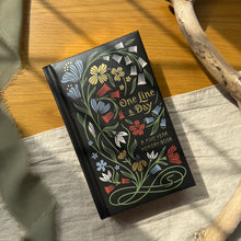 Load image into Gallery viewer, Floral notebook titled 'One Line a Day' on a wooden surface
