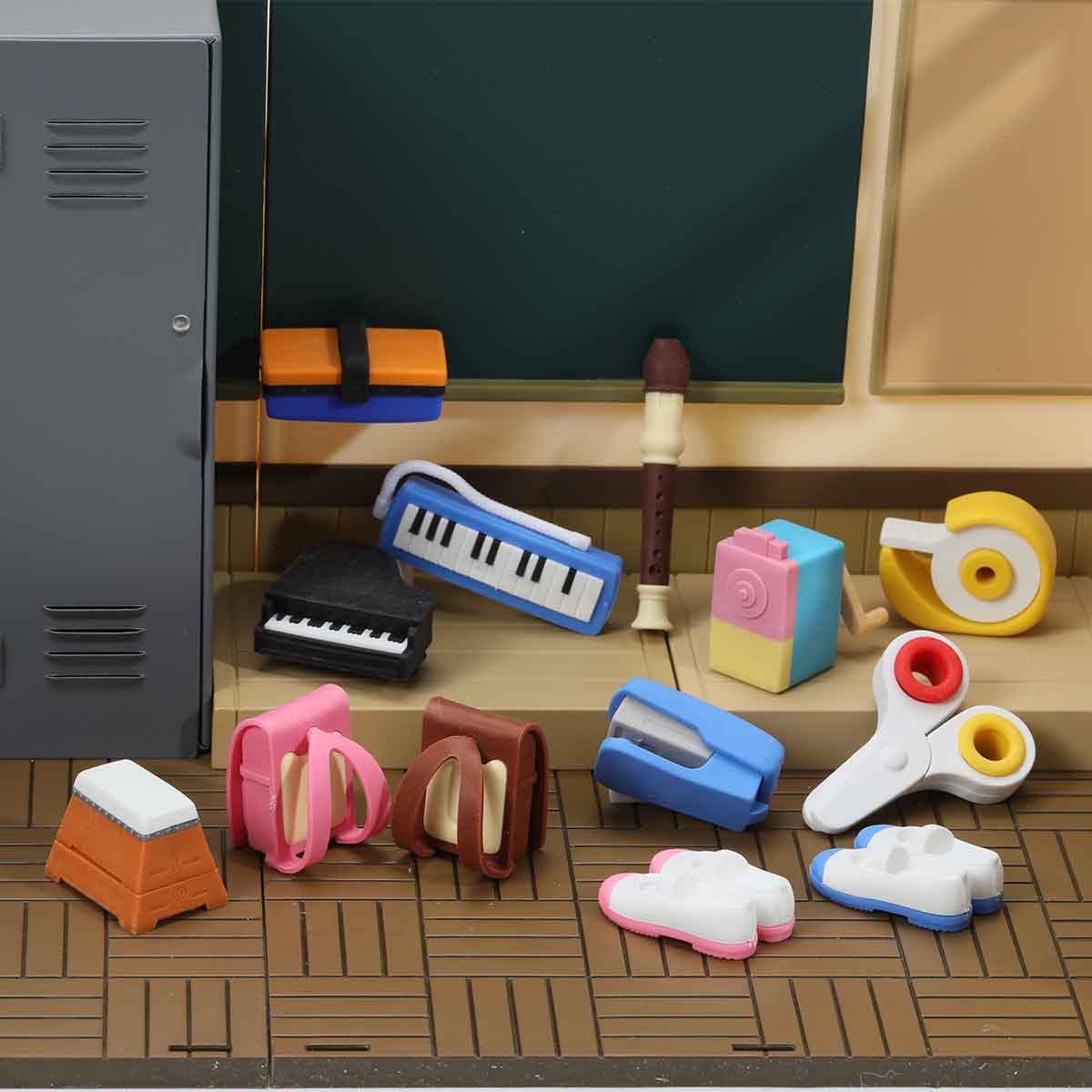 Collection of colorful stationery items on a desk with a blackboard in the background.