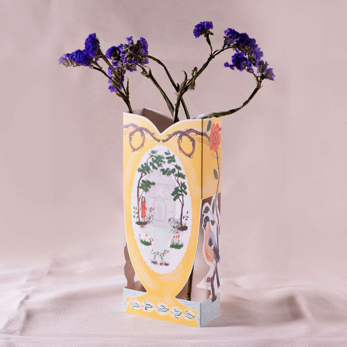 Decorative paper vase with floral design and purple flowers on a light pink background