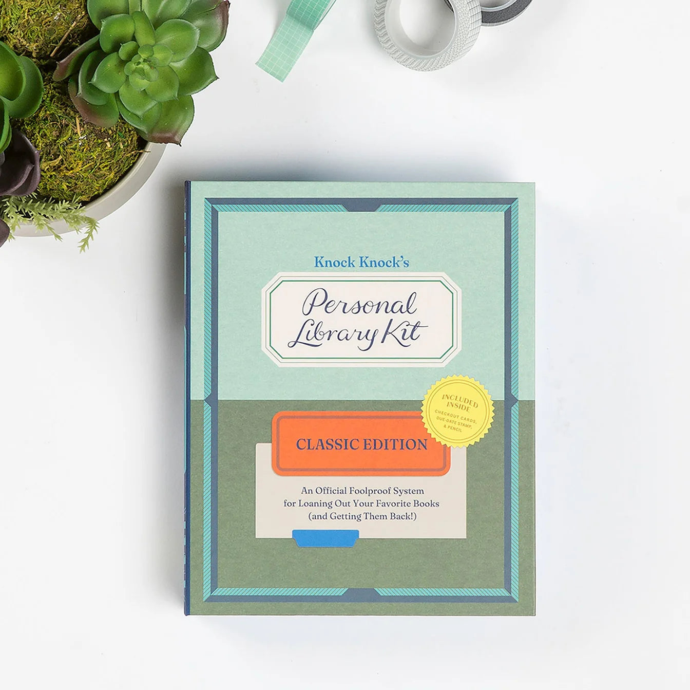 Knock Knock's Personal Library Kit on a white surface with a plant in the corner.
