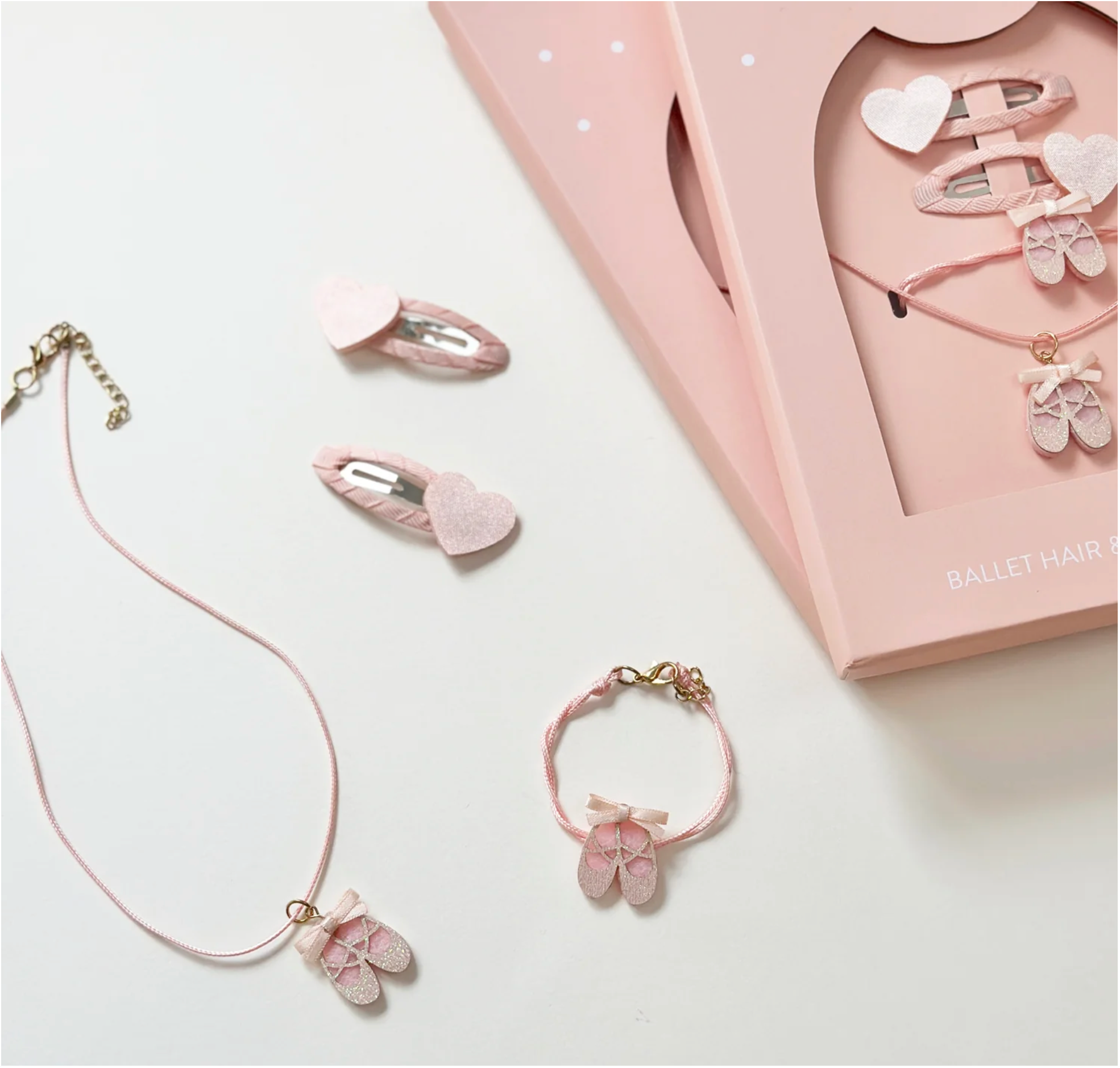 Pink jewelry set with ballet-themed hair clips and necklace on a white background