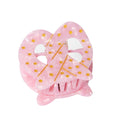 Pink pretzel-shaped hair clip with gold polka dots on a white background