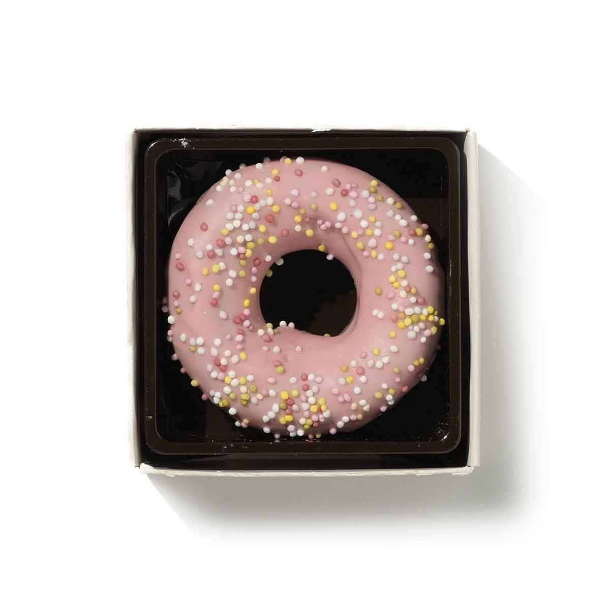 Pink chocolate donut with sprinkles in a black box on a white background