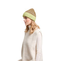 Woman wearing a beige knit beanie and white sweater on a white background