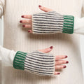Striped green and gray fingerless gloves worn on a person's hands against a neutral background.